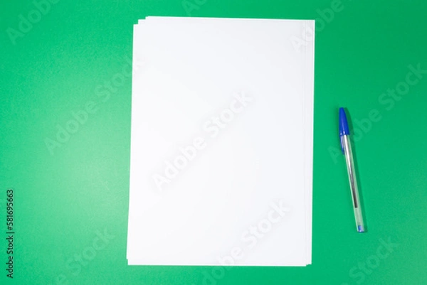 Fototapeta empty white paper sheet and a pen on green background. Mockup