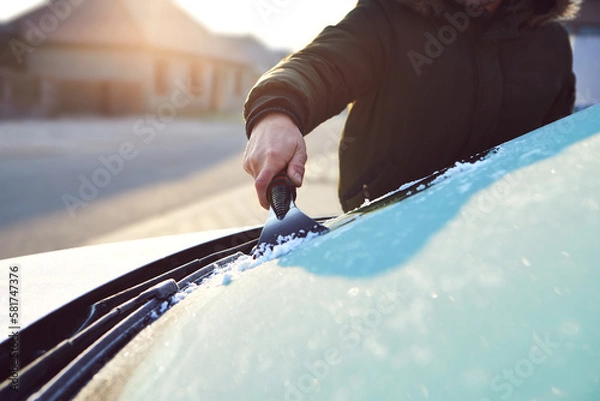 Obraz A man scratches the front window of his car on a cold winter morning
