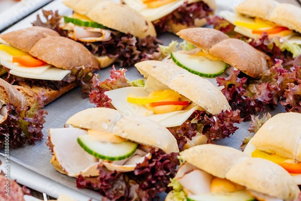 Obraz Nahaufnahme von belegten Brötchen mit Käse und Schinken auf Häppchen Platte beim Party oder Hochzeitsfeier Buffet dekoriert mit Gurken und Paprika