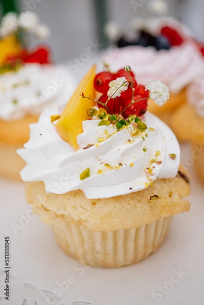 Obraz Cupcake oder Muffin aus Vanilleteig mit Creme Topping und Mango sowie Johannisbeeren Dekoration