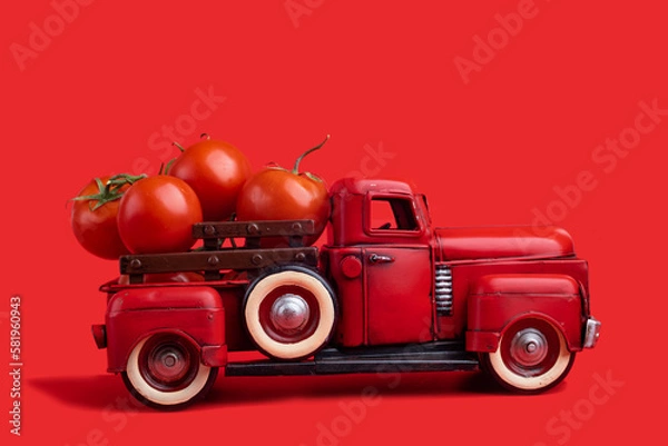 Fototapeta The red truck delivers fresh tomatoes. Vintage red toy truck on a red background.