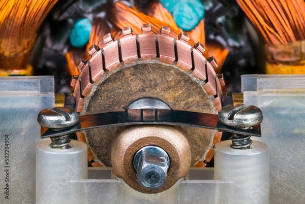 Fototapeta Closeup of commutator copper segments and plain bearing bronze housing in plastic pillow block. Steel flat leaf spring with screws inside old blender electric motor with rotor and stator wire winding.