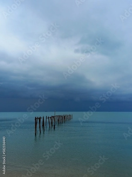 Fototapeta Ocean landscape with dark stormy sky and ruined jetty at Bophut beach on Koh Samui island in Thailand.
