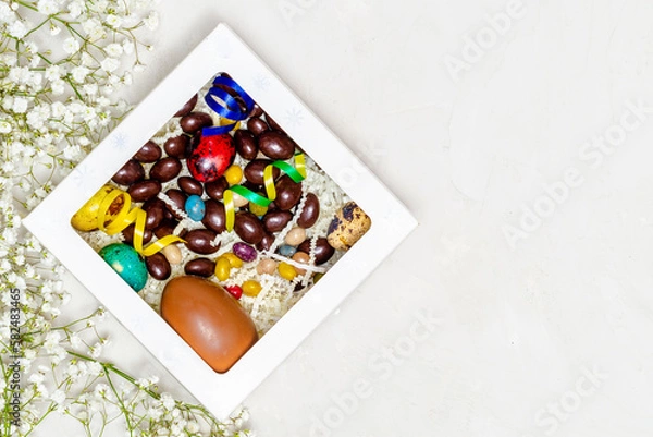 Fototapeta Festive Easter background. Easter colorful eggs with flowers on a white table. Flat styling