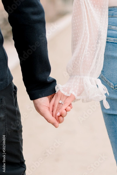 Obraz An engaged couple hold hands while they walk.
