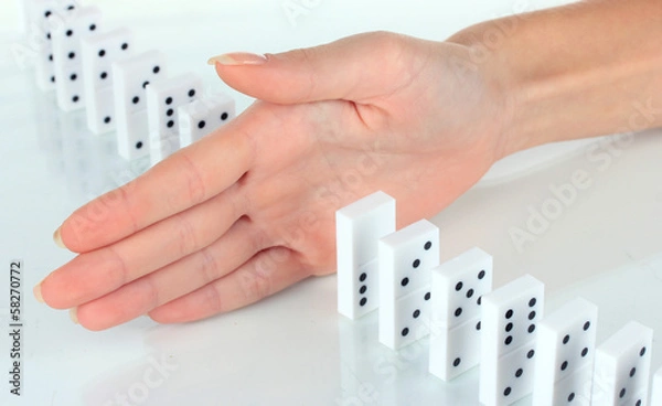 Obraz Hand stopping dominoes falling isolated on white