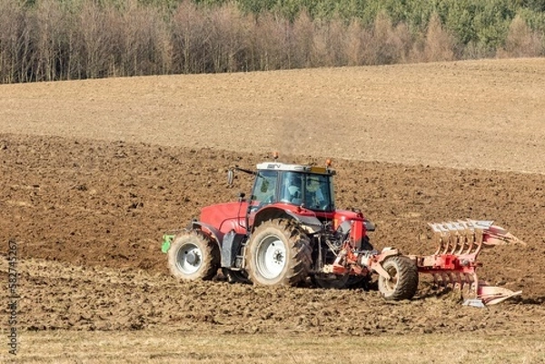Fototapeta Tractor plowing fields. Spring work on the farm in the Czech Republic. Agricultural landscape. Preparation for sowing grain.
