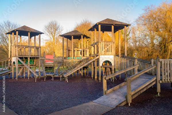 Fototapeta Children's playground wooden play structure fort with ramp, slide, ladder, bridge and hanging ropes.