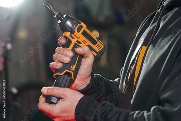 Fototapeta a man inserts a replacement battery into an electric wrench