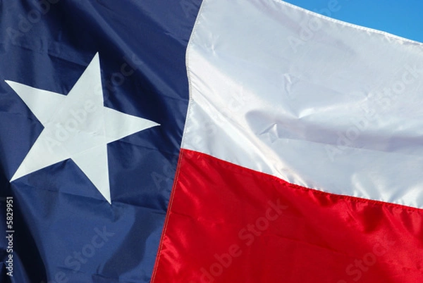 Obraz A new flag is replacing an old worn flag.