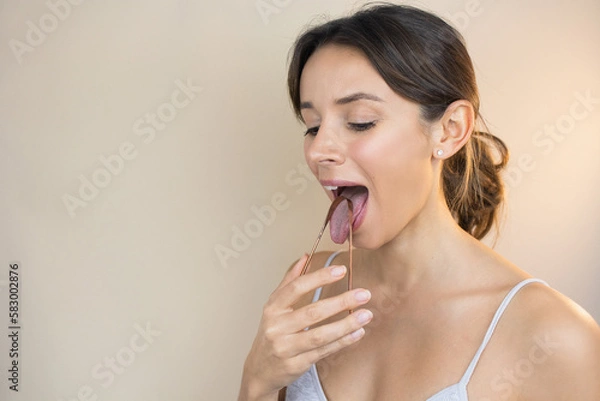 Fototapeta Woman Scraping Tongue with Copper Tongue Scraper Looking Happy and Healthy Oral Care Oral Hygiene Ayurveda