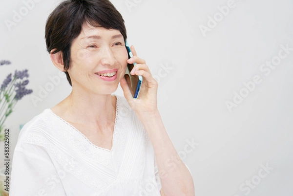 Fototapeta 家でスマホで電話する中年女性