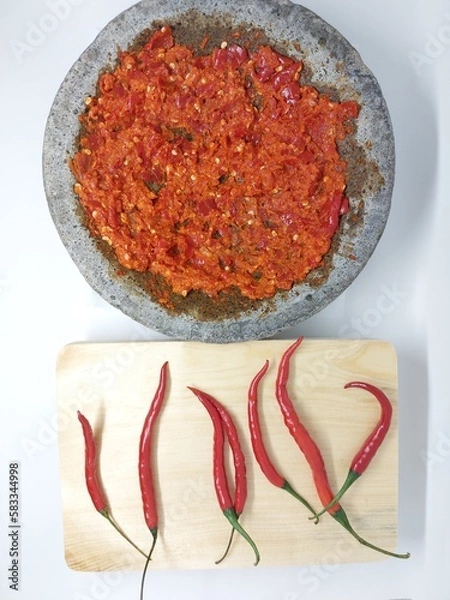 Fototapeta Indonesian Sambal Geprek chili sauce with tomato and garlic chili serve on pestle mortar stone called cobek