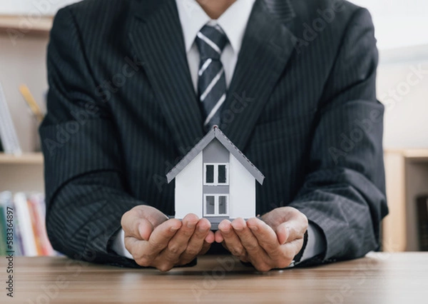 Obraz Concept of home and real estate Property insurance. Close up businessman of  hands sheltering modern house. .