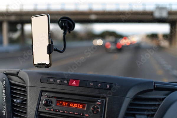 Fototapeta front of high van interior with phone hooked in the window for gps, in white mockup. road starting to get dark, cars with lights and there is still light. Radio on bt audio