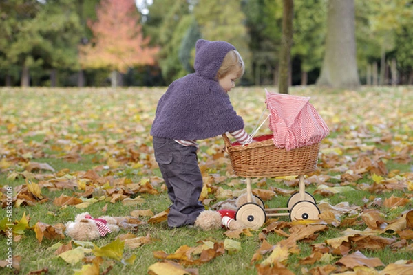 Obraz little girl playing with a pram in the park