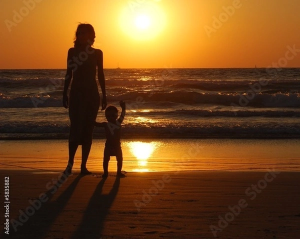 Obraz young woman with small child on the sea shore on sunset