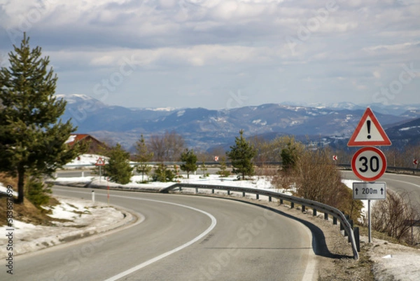 Obraz a traffic warning sign before a sharp bend in the road