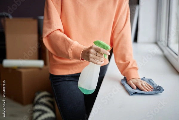Fototapeta Close-up of young woman using detergent to do housework in her new apartment after relocation