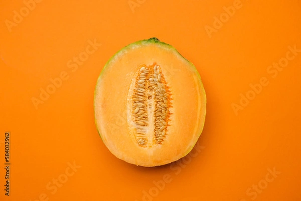 Fototapeta Half melon fresh organically grown on orange background. Sweet and juicy summer fruit. Cool minimal flat lay, copy space