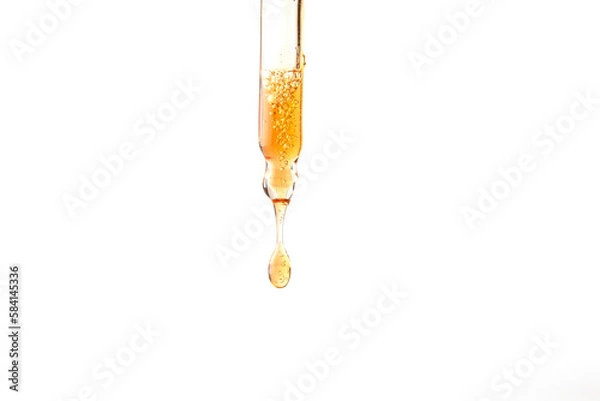 Fototapeta Dropper pipette with orange liquid drop on the whte isolated background. Oil, serum, acid cosmetic sample Close up.Copy space