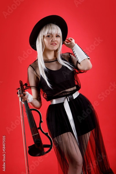 Fototapeta Violinist woman in the stage costume on the red background.