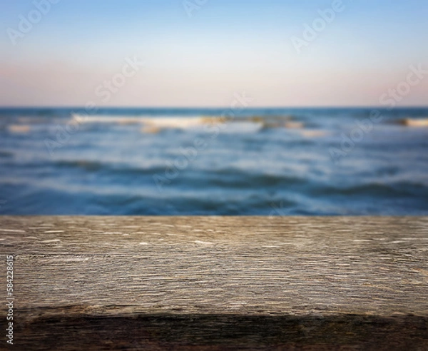Fototapeta Natural, abstract, unfocused background. Seascape. An empty wooden base, a wooden table, a tabletop against the background of sunset, dawn on the seashore. Copy space