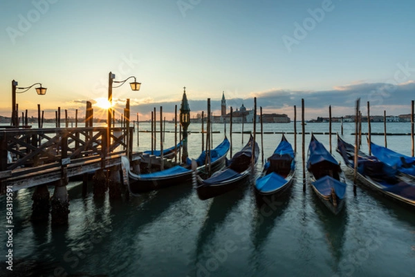Fototapeta Venice  gondala's Italy. Sunrise in Venice with gondala's in the foreground on the canal and the sunrise in the backgound on blue sky.