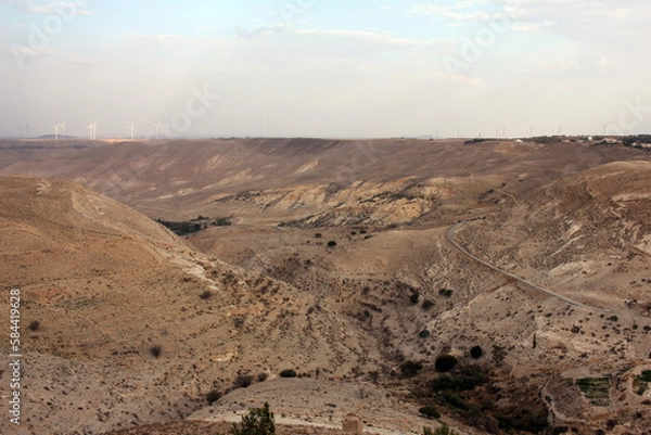 Fototapeta Desert landscape view of sunny rocky cliff with wind turbines in view taken from Shobak Castle, Jordan