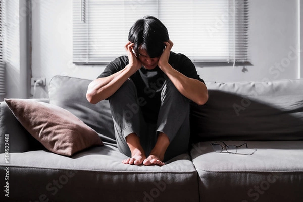 Fototapeta Close up of asian man with depression sitting alone on sofa