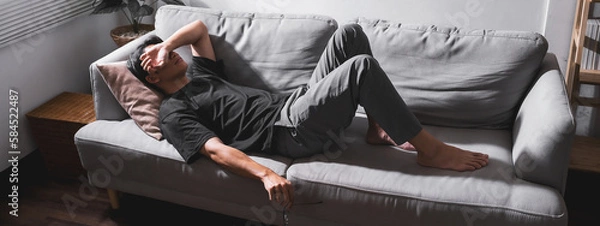 Fototapeta Stressed man lying on sofa holding glasses for relax. For banner design