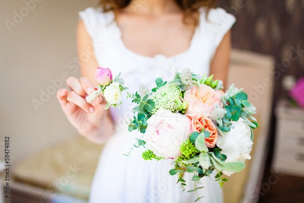 Fototapeta bride holding a wedding bouquet and a buttonhole
