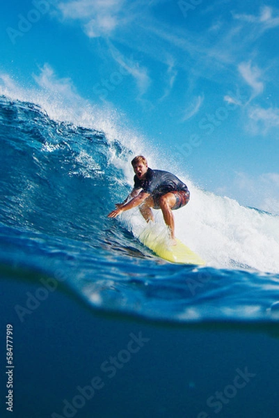 Fototapeta Surfer rides the wave. Exited man surfs the ocean wave in the Maldives, splitted underwater view