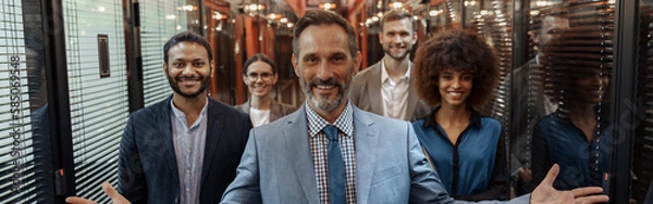 Obraz Group of happy, motivated business people standing together at office with their leader