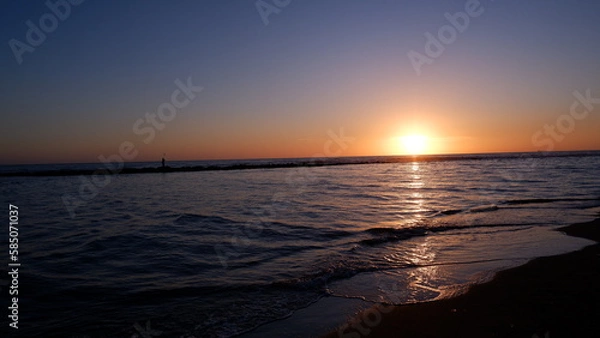 Fototapeta Sunset on the sea, waves crashing on the beach and the silhouette of Poseidon.