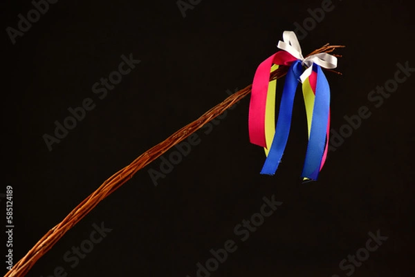 Obraz Traditional Czech Easter whip with colored ribbons 
from willow branches on the black background 