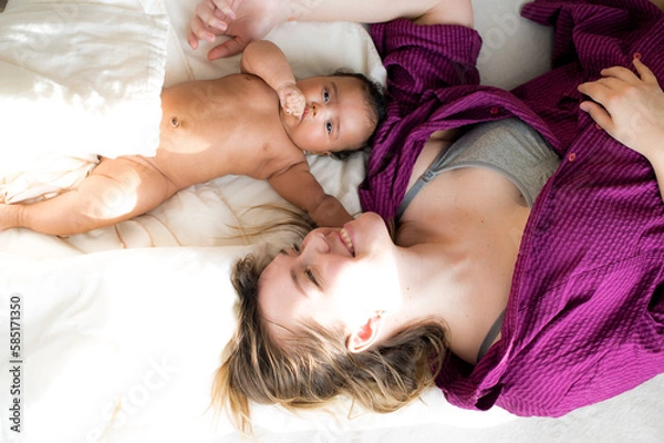 Fototapeta A bright portrait of a happy mother and her baby