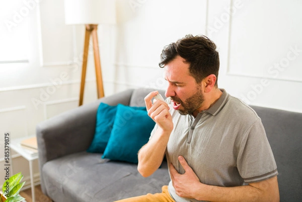 Fototapeta Ill man suffering from asthma using an inhaler