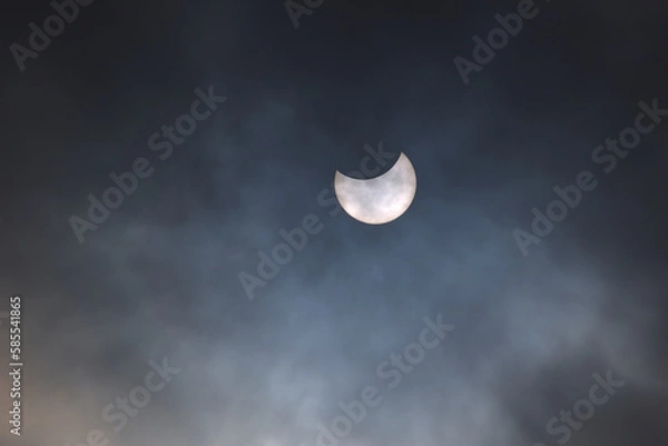 Fototapeta Partial eclipse of the sun on a cloudy sky with visible sunspots on its surface.