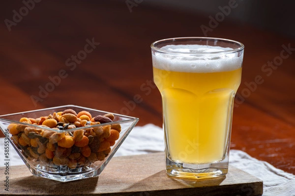 Fototapeta Glass of Belgian white unfiltered beer with notes of coriander and orange peer and different snack nuts