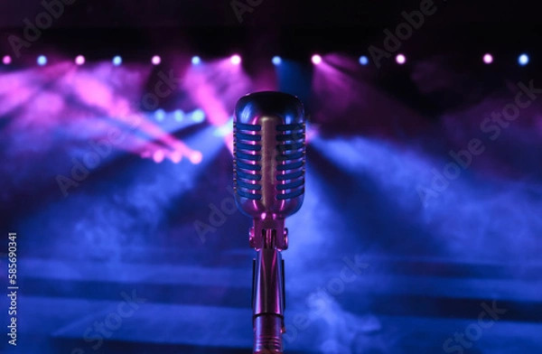 Fototapeta Professional vintage microphone on a concert stage before the performance with blue and pink lightning. Retro style vocal mic in the spotlights for festival, jazz club or podcast background