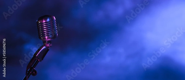 Fototapeta retro microphone in the dark with blue light from stage spotlights. Vintage mic on dark blue background for music live, music festival, karaoke or podcast banner with copy space.