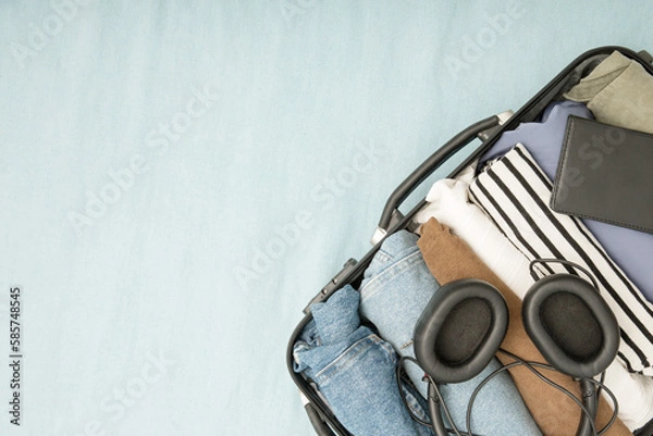 Fototapeta An open suitcase with neatly folded konmari clothes vertically. The concept of packing clothes for a trip, vacation or business trip. Copy space, top view, minimalism