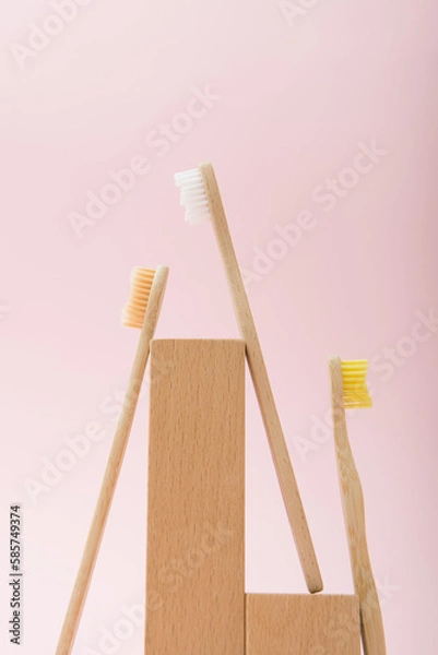 Fototapeta Composition of bamboo toothbrushes and wooden podium blocks. The concept of an eco-friendly lifestyle and the reduction of plastic waste. Minimalism, vertical photo