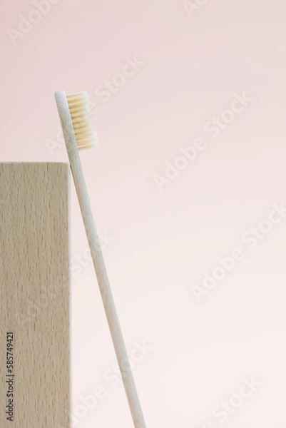Fototapeta Composition of bamboo toothbrush and wooden podium block. The concept of an eco-friendly lifestyle and the reduction of plastic waste. Minimalism, vertical photo