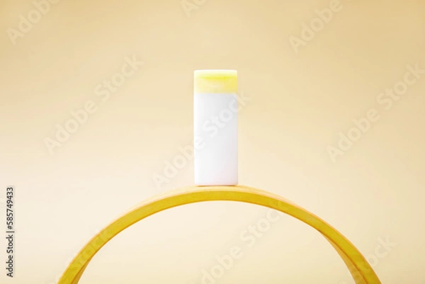 Fototapeta White bottle with cosmetic lotion or cream on the arc. Unusual composition, minimalism, mockup.
