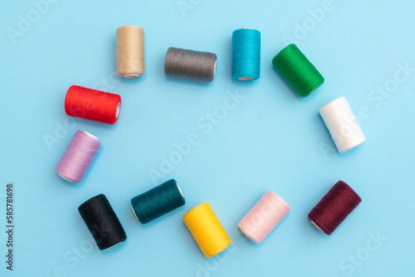 Fototapeta Randomly arranged colored spools of sewing threads with space in the center close-up