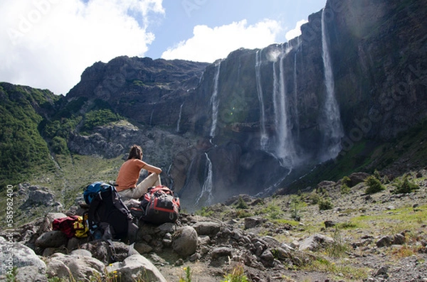 Fototapeta woman backpacker seated looking at the waterfalls of the volcano cerro tronador