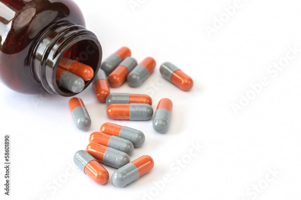 Obraz Grey and orange pills with bottle on white