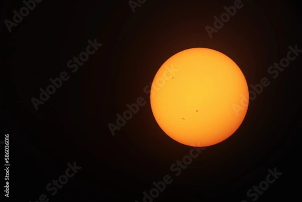 Obraz Orange sun on a black background. Big yellow-orange sun with sunspots photographed through a telescope filter on a black background with copy space. selective focus